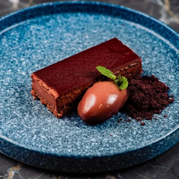 Rich chocolate dessert bar with a scoop of ice cream, mint leaf, and chocolate crumbles.